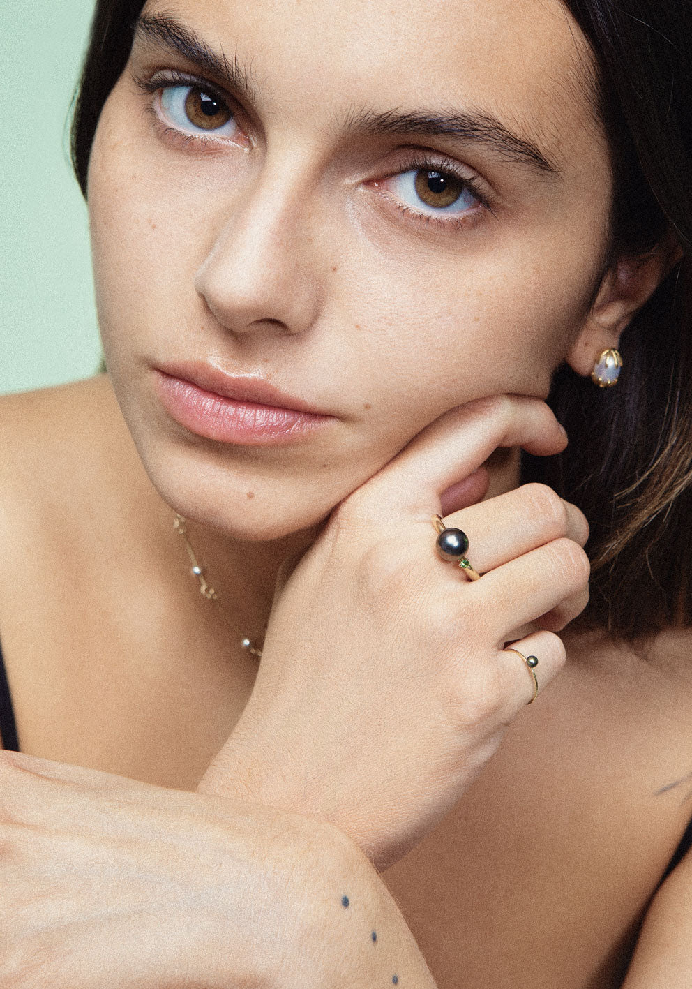 A pair of gold earrings featuring a white pearl in between, designed to resemble a chicken hatching from an egg. Handmade in Barcelona.