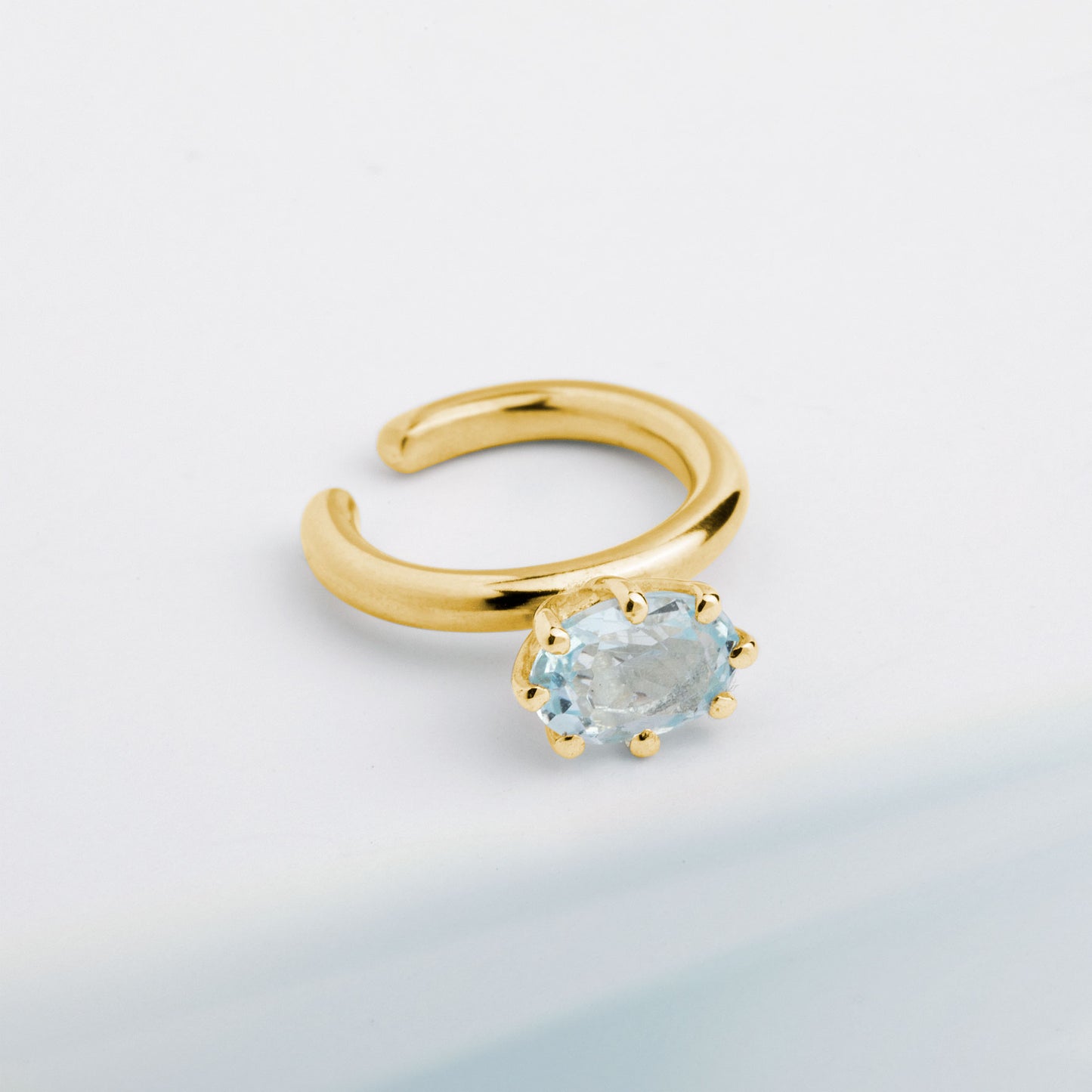 A ear cuff with Blue Topaz gemstone, made of 18k yellow gold plated silver. Handmade in Barcelona. No piercing needed.