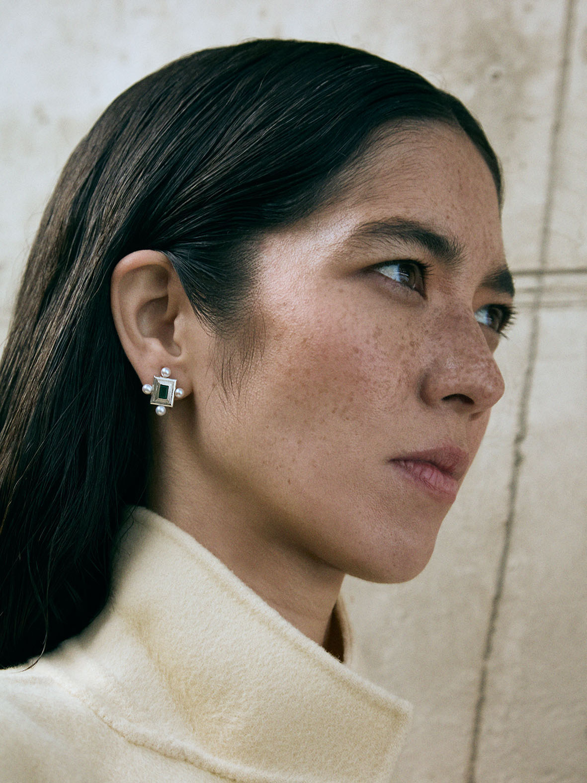 A pair of silver earrings featuring a geometric design with a central colored gemstone surrounded by pearls, set in a rectangular shape.