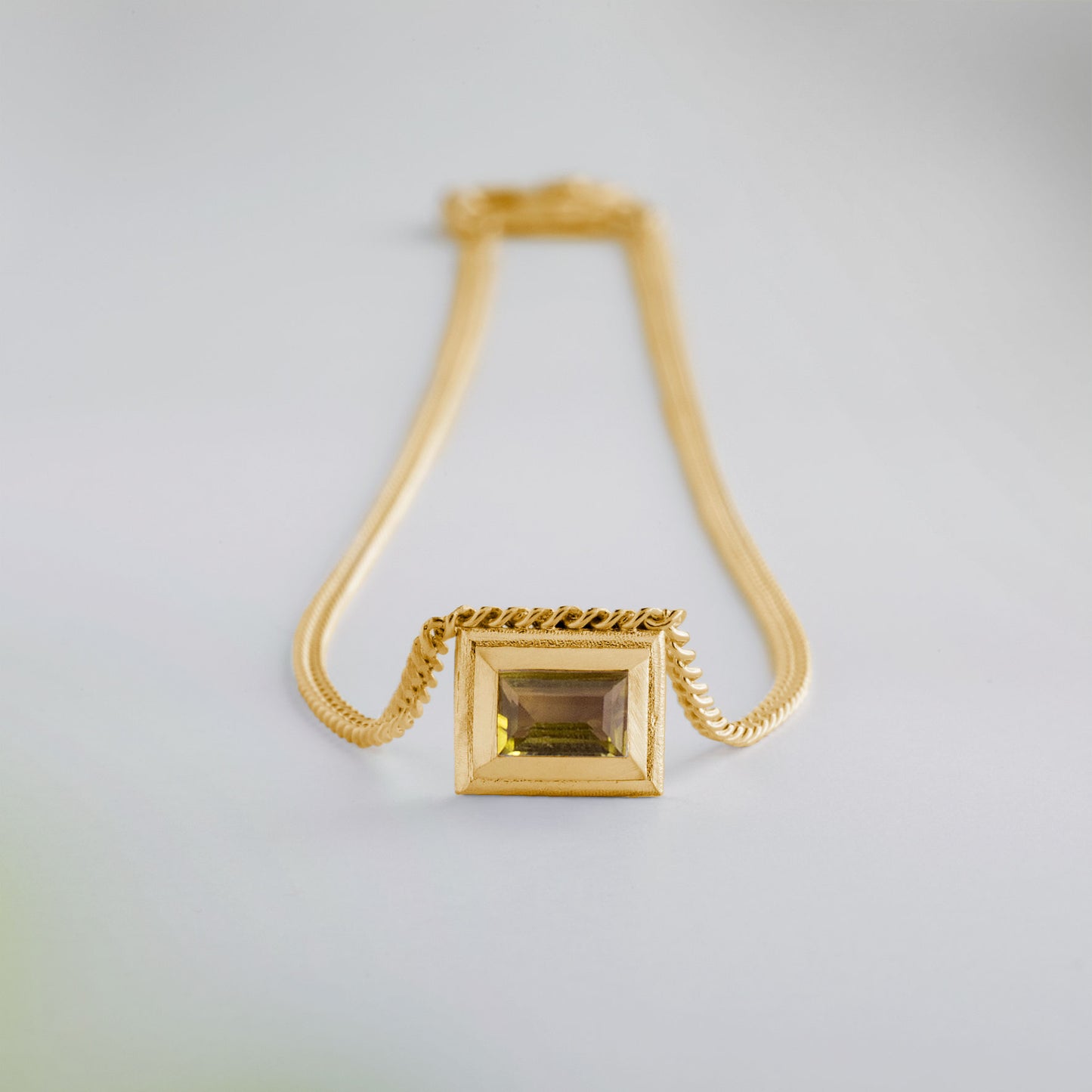 A gold plated silver necklace with a reversible pendant featuring a green Chrysoprase gemstone on one side and blue Topaz on the other designed for everyday wear.