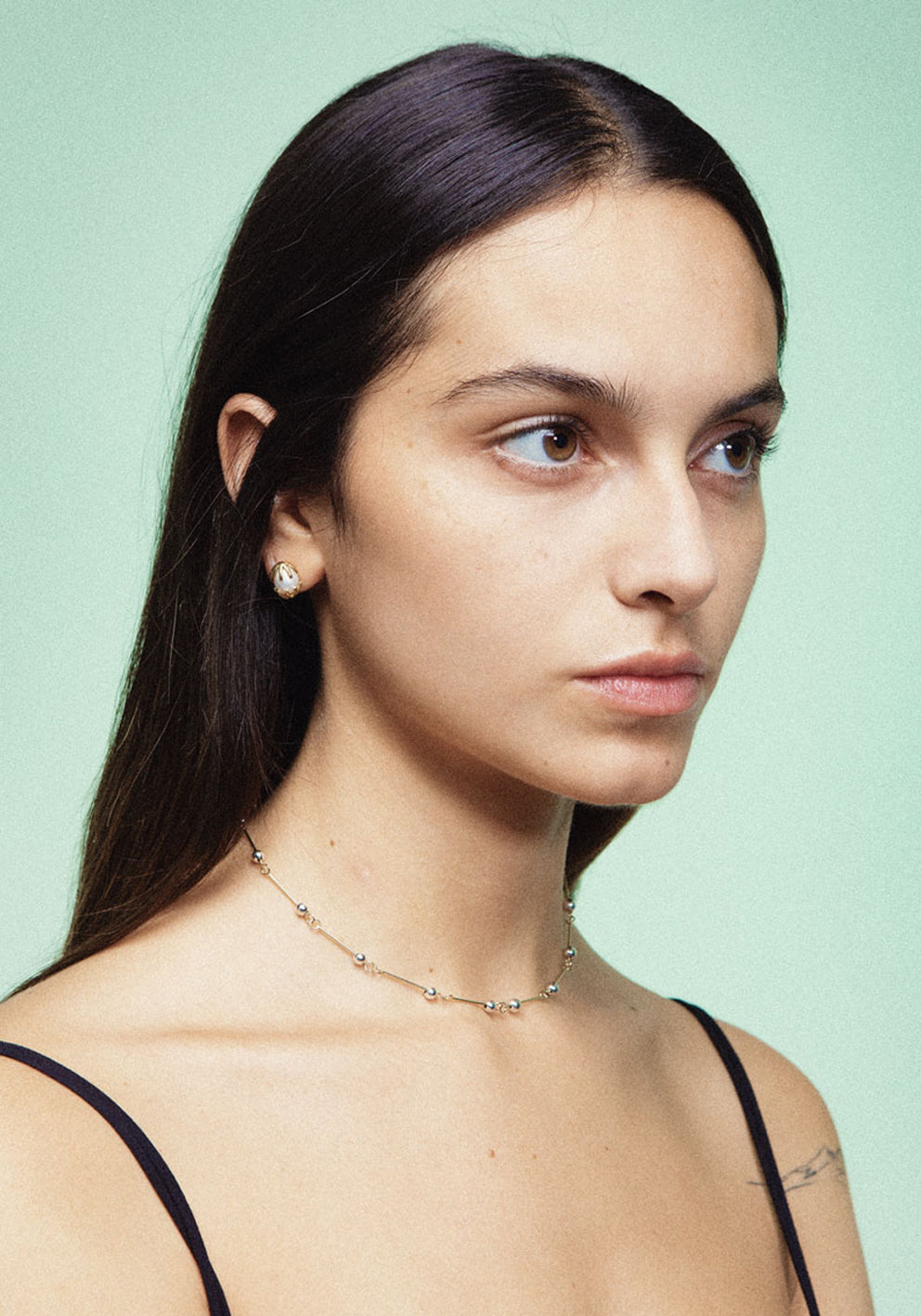 A pair of gold earrings featuring a white pearl in between, designed to resemble a chicken hatching from an egg. Handmade in Barcelona. 