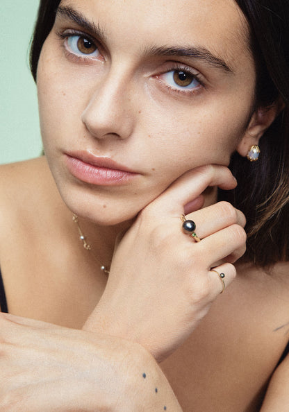 A ring with a large grey Freshwater Pearl set in a 18K gold wire, with a tall prong setting holding a bright green Tsavorite Garnet.