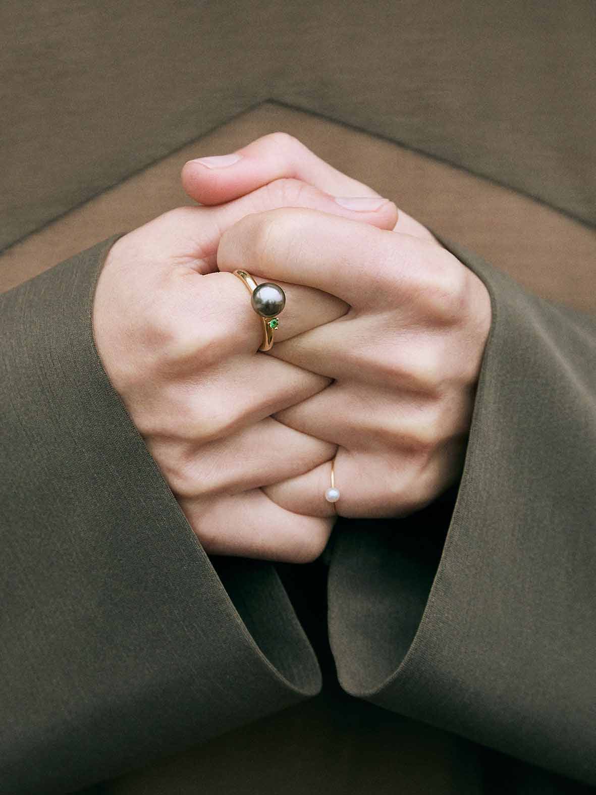A ring with a large grey Freshwater Pearl set in a 18K gold wire, with a tall prong setting holding a bright green Tsavorite Garnet.