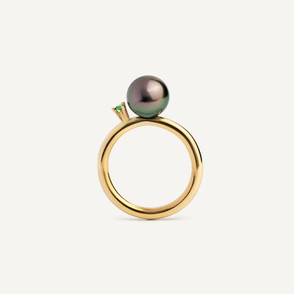 A ring with a large grey Freshwater Pearl set in a 18K gold wire, with a tall prong setting holding a bright green Tsavorite Garnet.