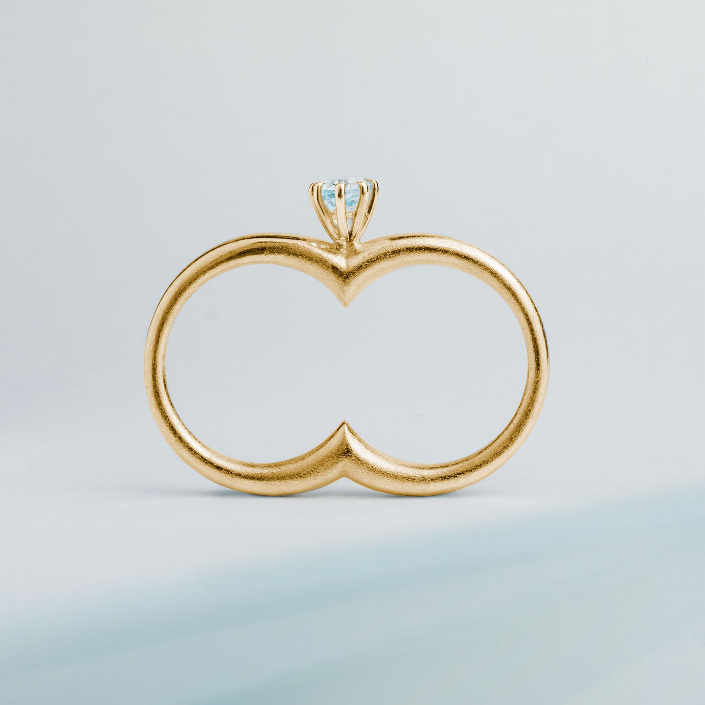 A gold plated silver ring with a double circle and a blue gemstone designed for two fingers.