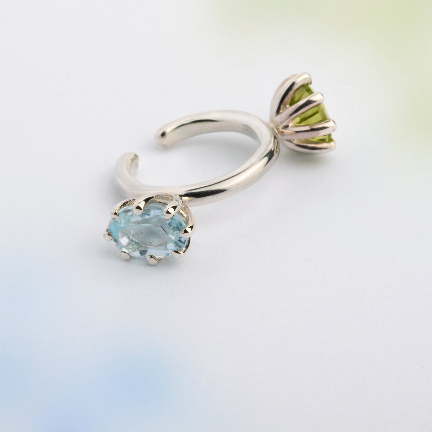 An ear cuff with 2 gemstones green Peridot and blue Topaz, made of silver. Handmade in Barcelona. No piercing needed. 