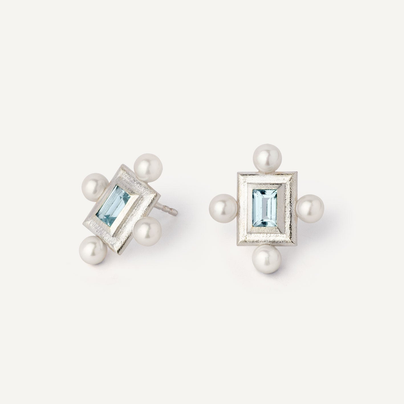 A pair of silver earrings featuring a geometric design with a central blue gemstone surrounded by pearls, set in a rectangular shape.