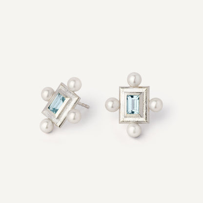A pair of silver earrings featuring a geometric design with a central blue gemstone surrounded by pearls, set in a rectangular shape.