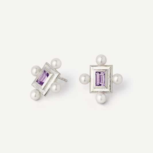 A pair of silver earrings featuring a geometric design with a central violet gemstone surrounded by pearls, set in a rectangular shape.