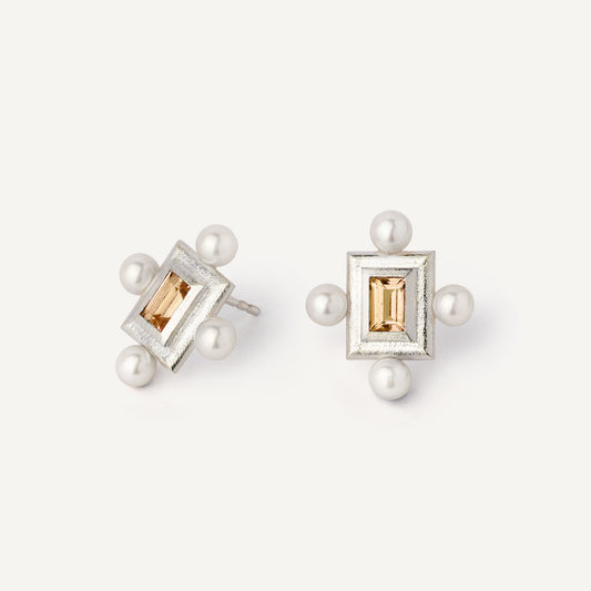 A pair of silver earrings featuring a geometric design with a central yellow gemstone surrounded by pearls, set in a rectangular shape.