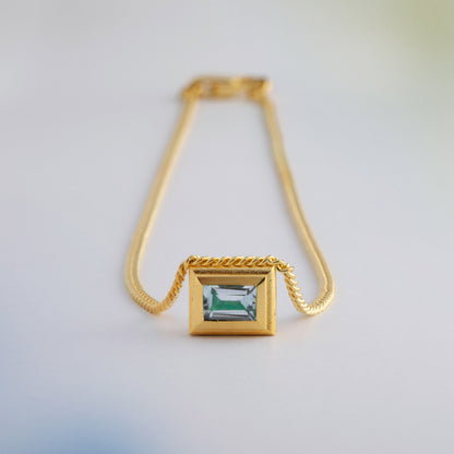A gold plated silver necklace with a reversible pendant featuring a green Chrysoprase gemstone on one side and blue Topaz on the other designed for everyday wear.