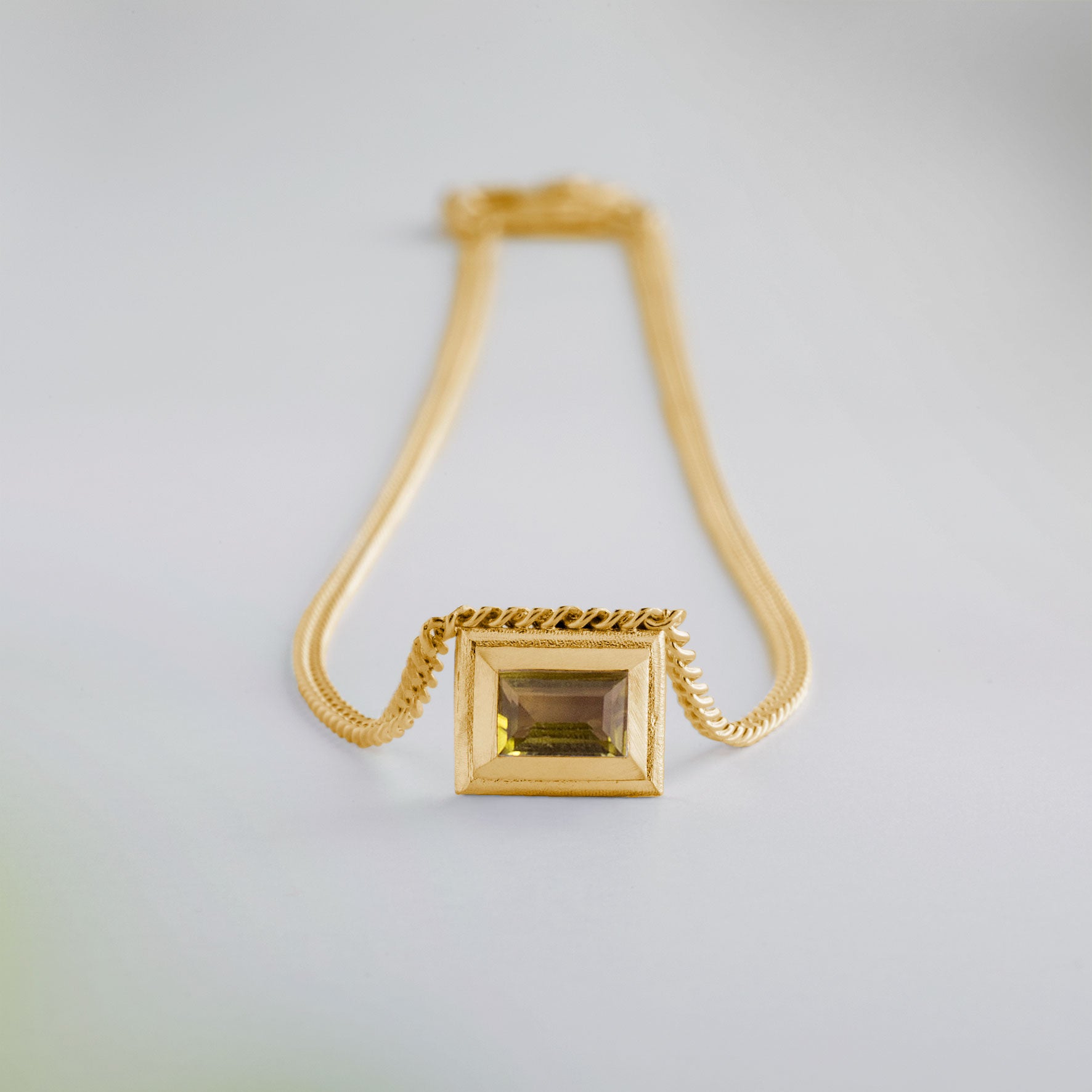 A gold plated silver necklace with a reversible pendant featuring a green Chrysoprase gemstone on one side and blue Topaz on the other designed for everyday wear.