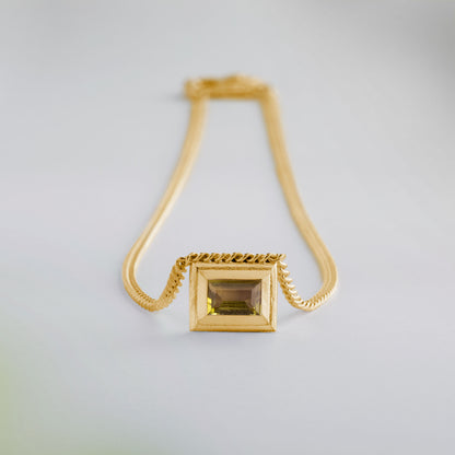 A gold plated silver necklace with a reversible pendant featuring a green Chrysoprase gemstone on one side and blue Topaz on the other designed for everyday wear.