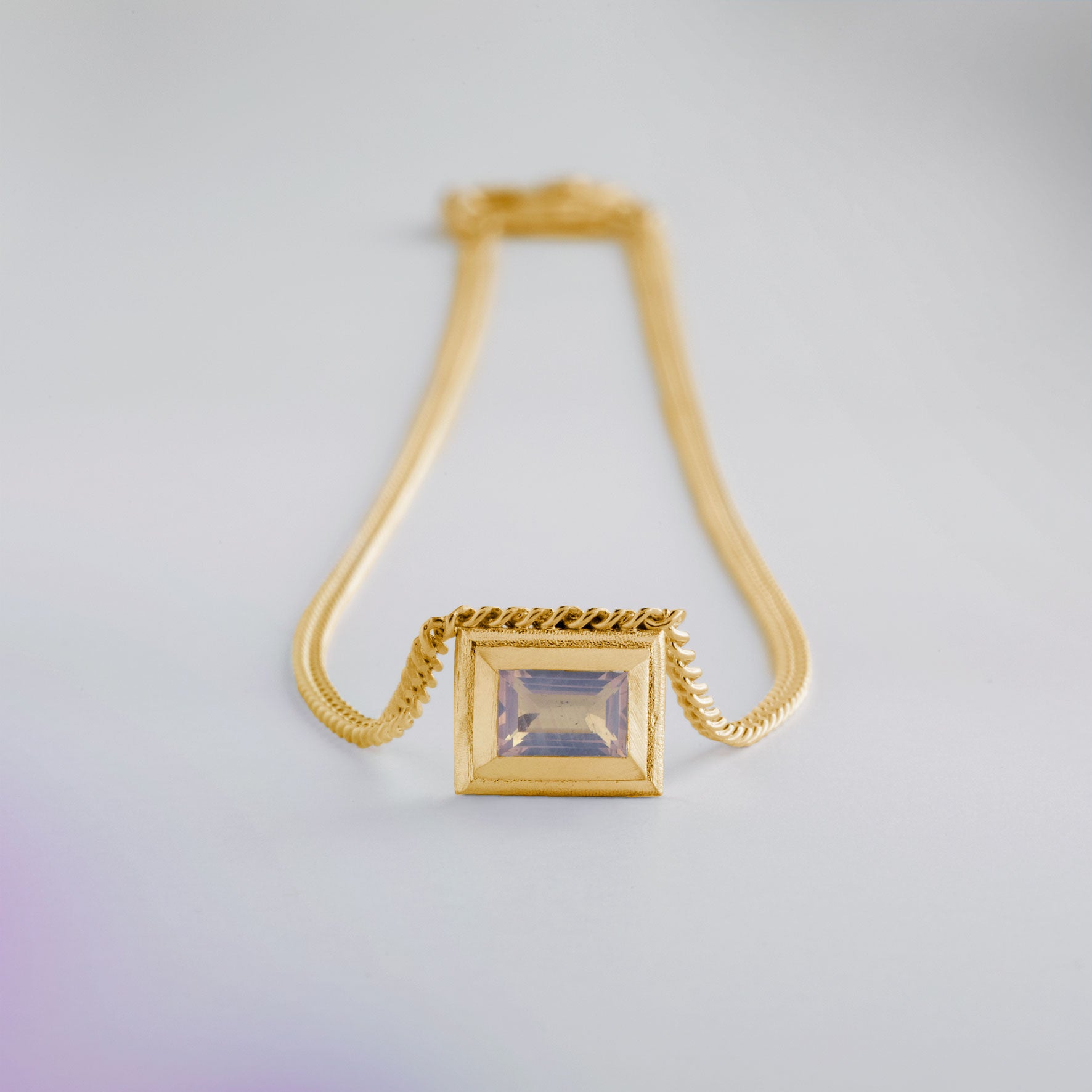 A gold plated silver necklace with a reversible pendant featuring a green Chrysoprase gemstone on one side and blue Topaz on the other designed for everyday wear.