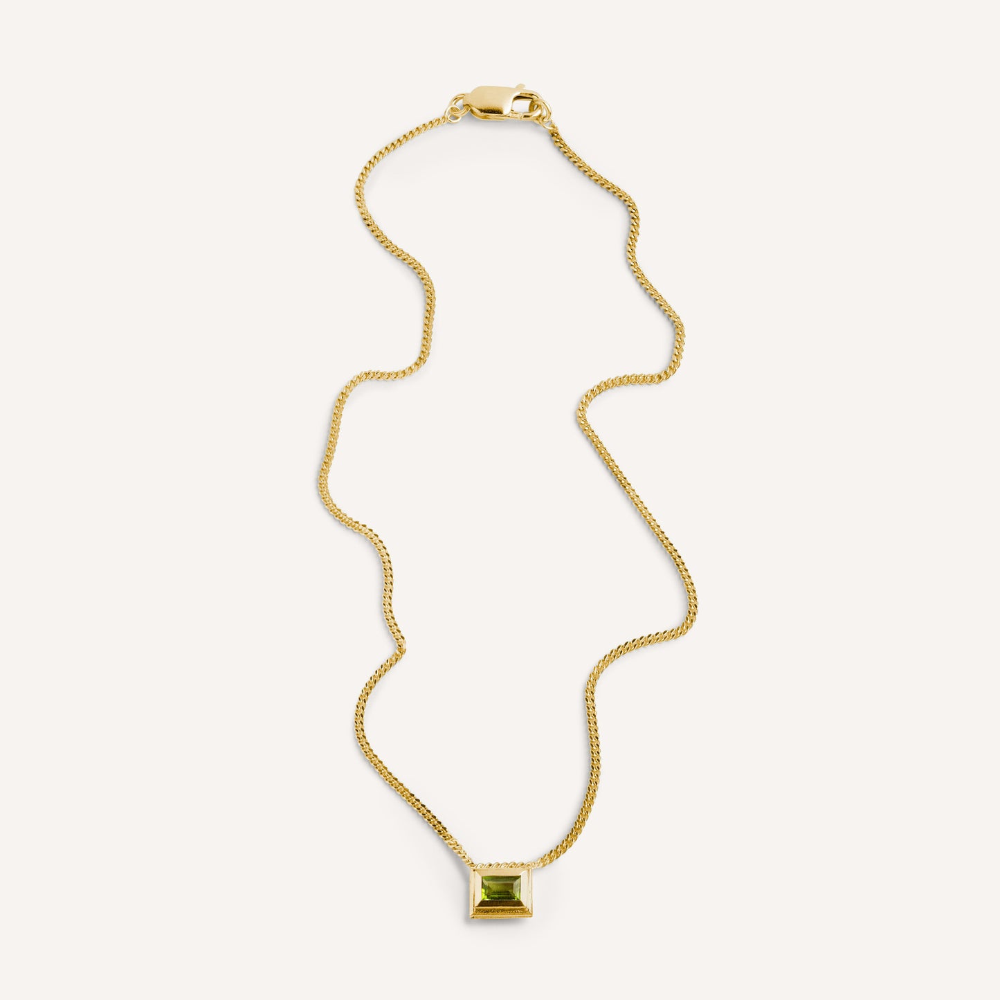 A gold plated silver necklace with a reversible pendant featuring a green Peridot gemstone on one side and violet Amethyst on the other designed for everyday wear.