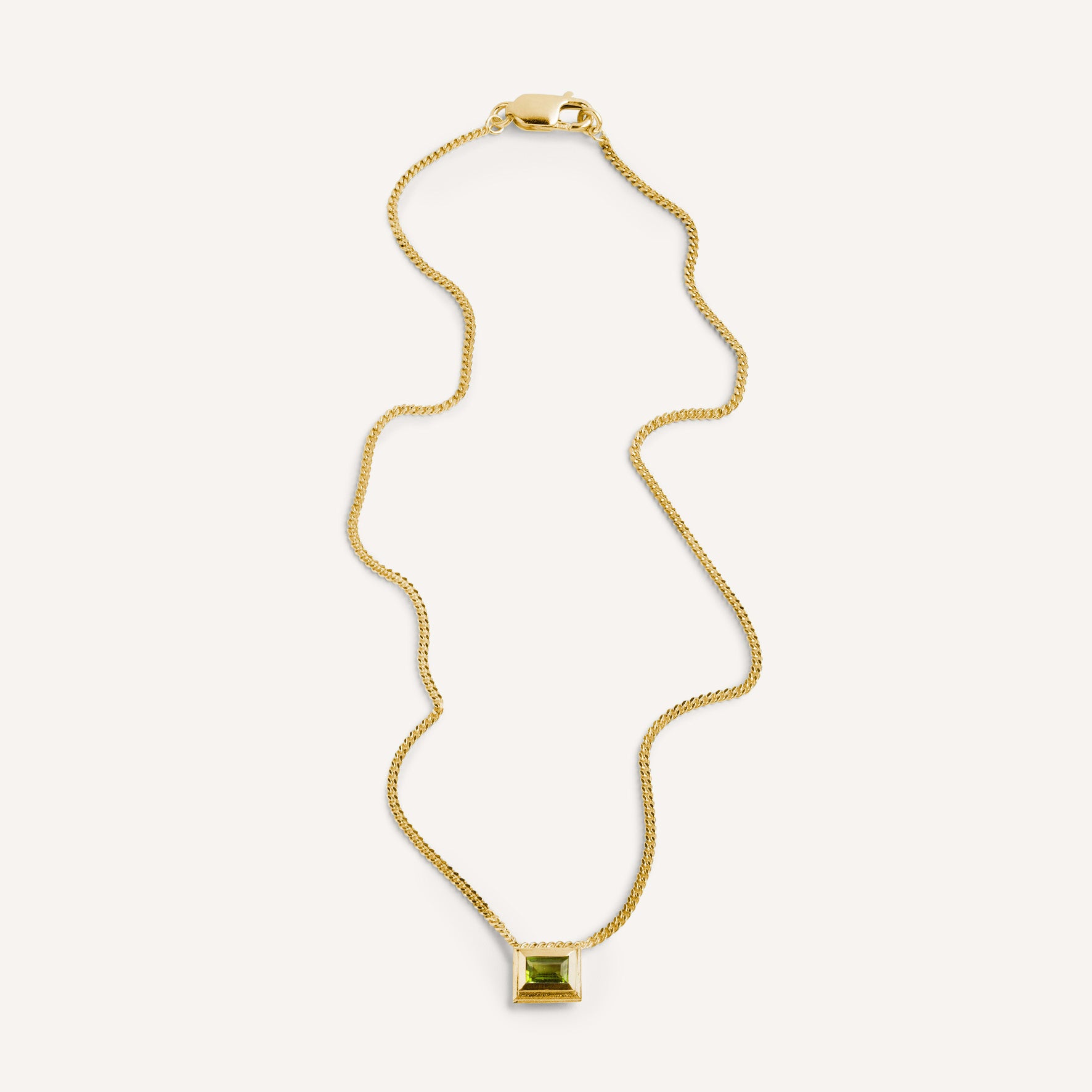 A gold plated silver necklace with a reversible pendant featuring a green Peridot gemstone on one side and violet Amethyst on the other designed for everyday wear.