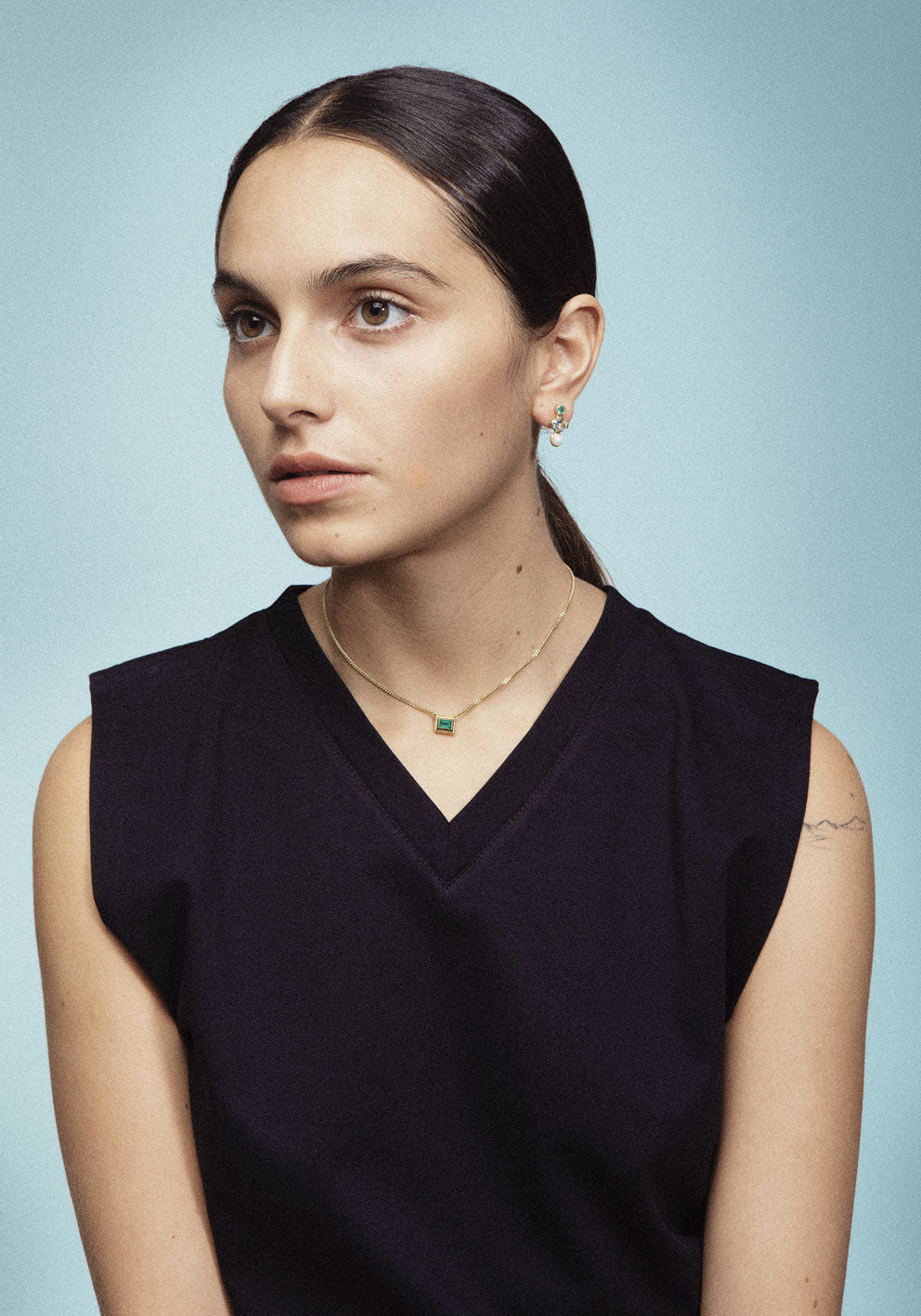 A silver necklace with a reversible pendant featuring two colored gemstones on on two sides designed for everyday wear.