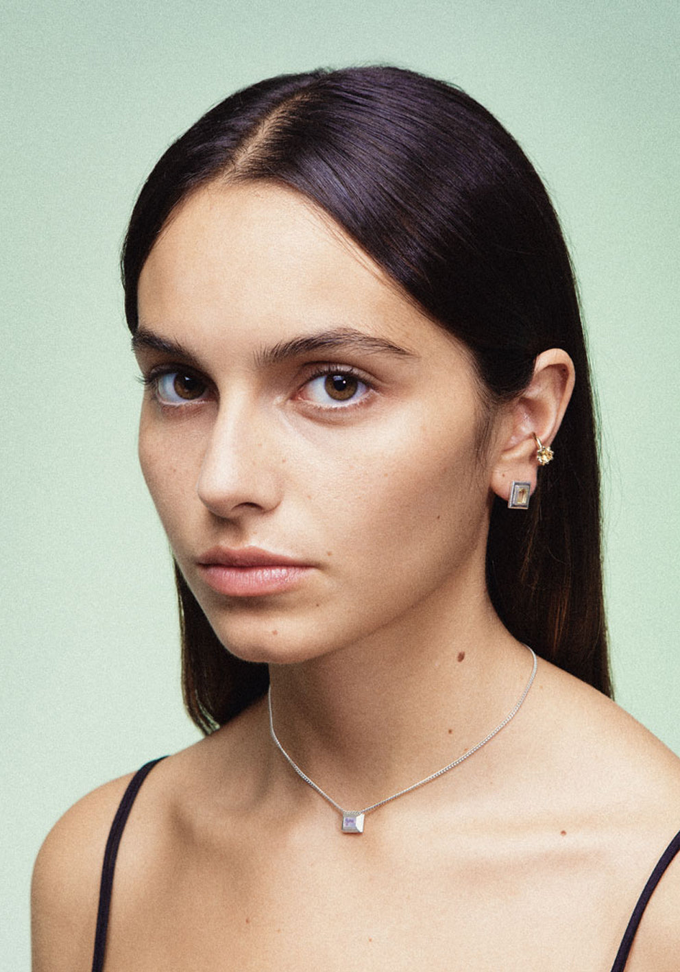 A silver necklace with a reversible pendant featuring a green Peridot gemstone on one side and violet Amethyst on the other designed for everyday wear.