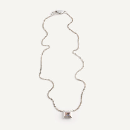 A silver necklace with a reversible pendant featuring a green Peridot gemstone on one side and violet Amethyst on the other designed for everyday wear.