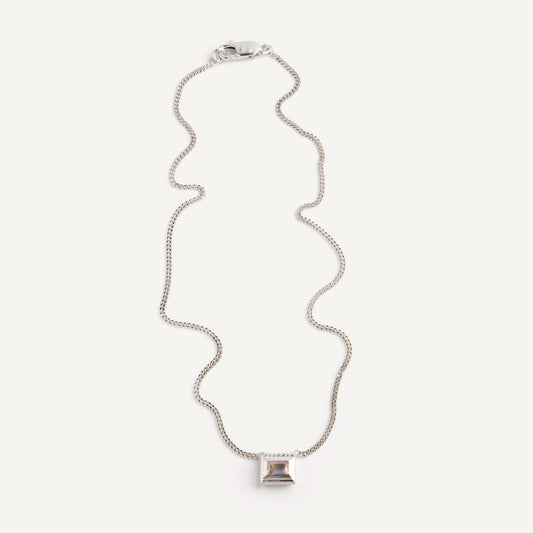 A silver necklace with a reversible pendant featuring a green Peridot gemstone on one side and violet Amethyst on the other designed for everyday wear.