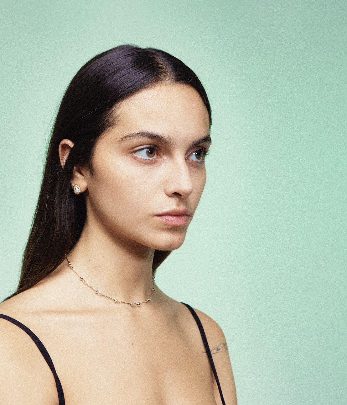 A necklace with small silver spheres strung on silver wire, with a focus on the interplay of light and shadow.