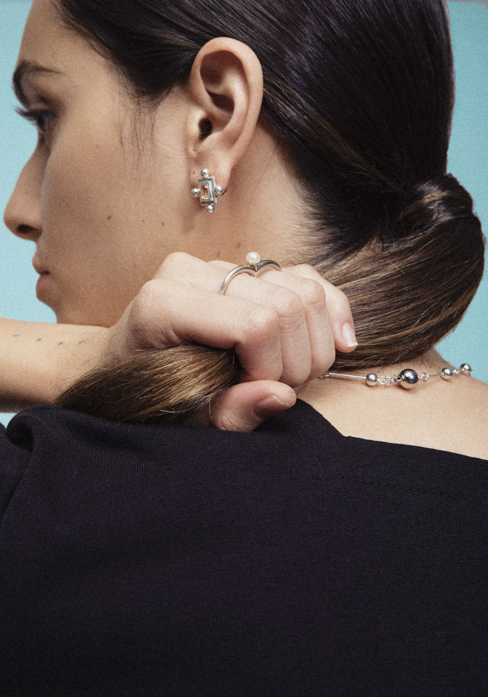 A necklace with small silver spheres strung on silver wire, with a focus on the interplay of light and shadow.